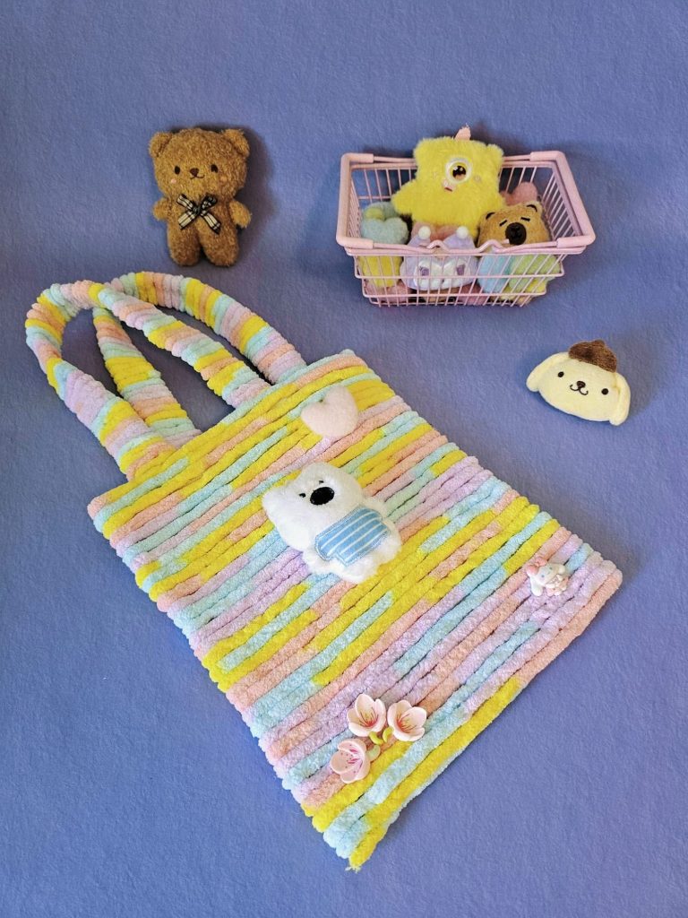 A colorful handmade bag with many plushies lying on a purple surface