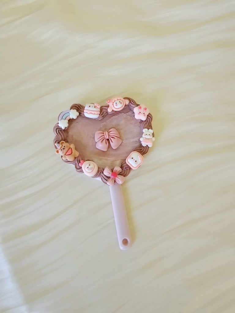 a pink small handholding mirror with deocden craft style