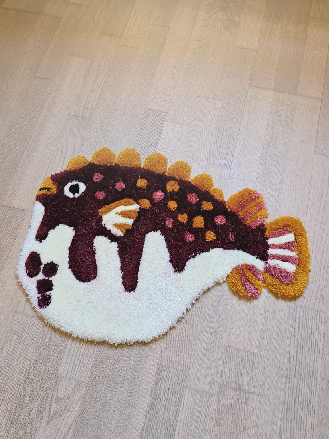A red and white rug about big fat fish lying on the ground